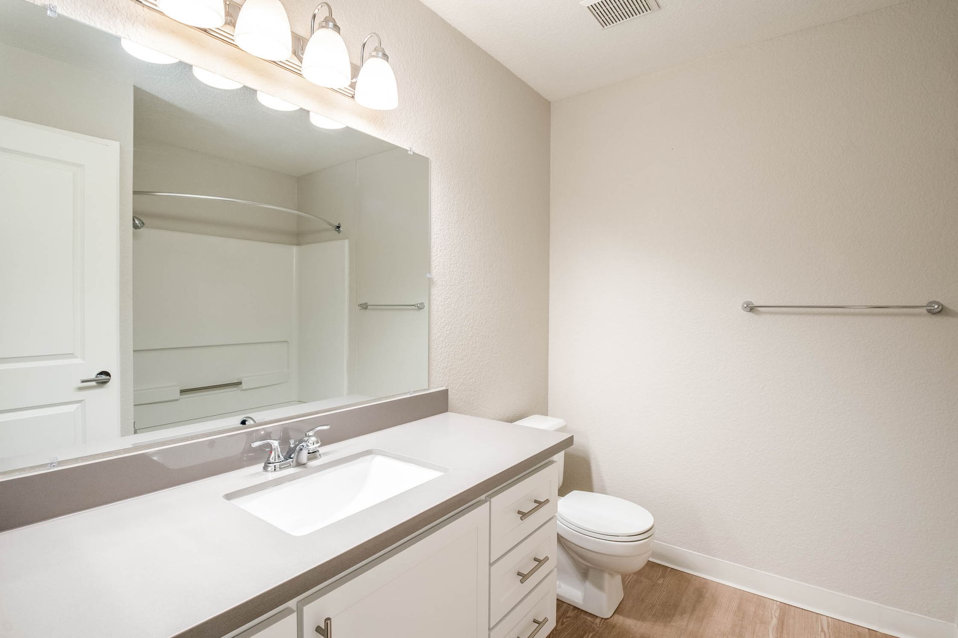 Bathroom vanity with sink, mirror, and toilet in an apartment at Shore Park at Riverlake.