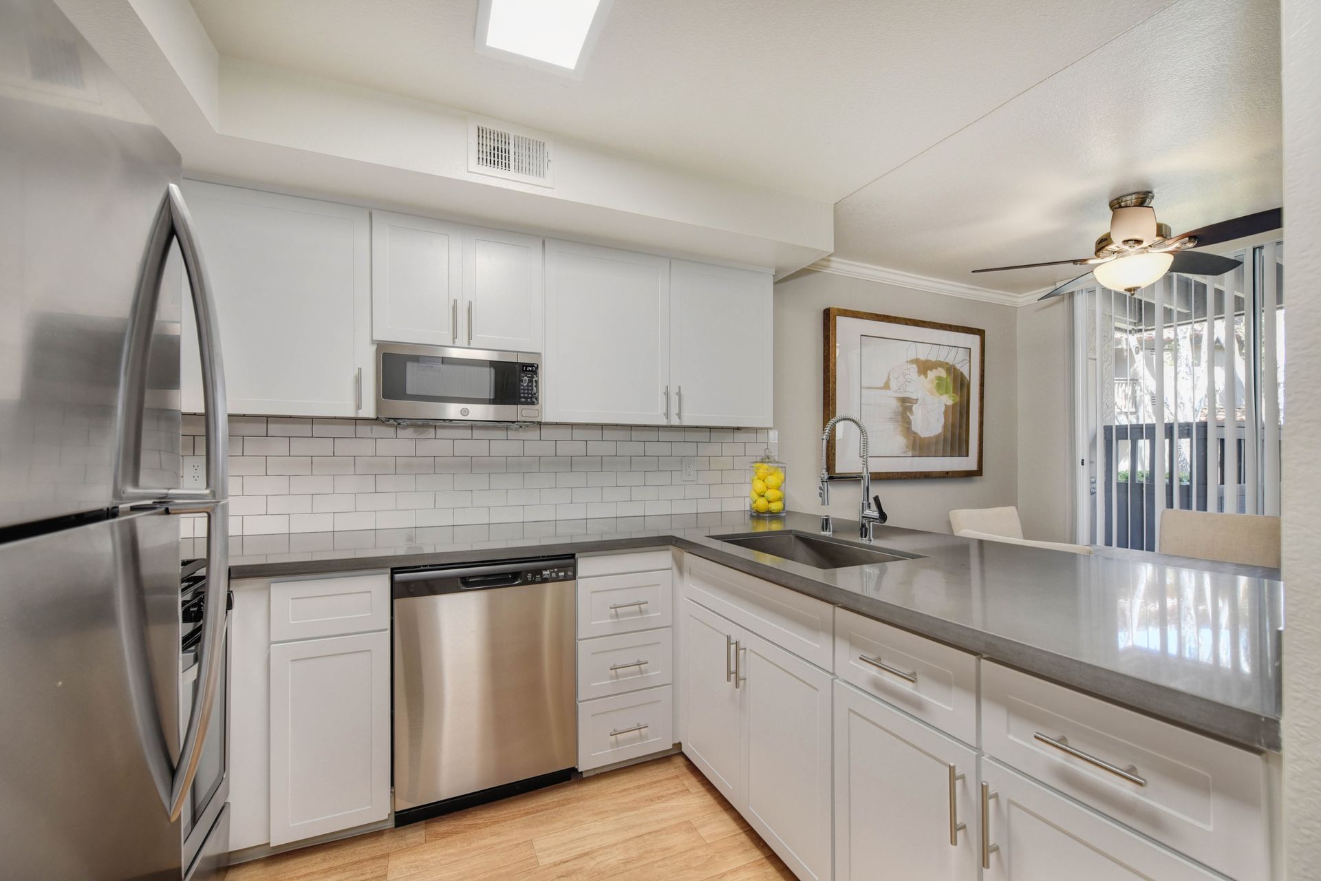 Bright kitchen with white cabinets, stainless steel appliances, and an island with sink at Shore Park at Riverlake.
