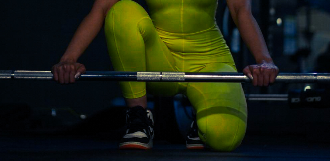 a woman is squatting down while holding a barbell in a gym .