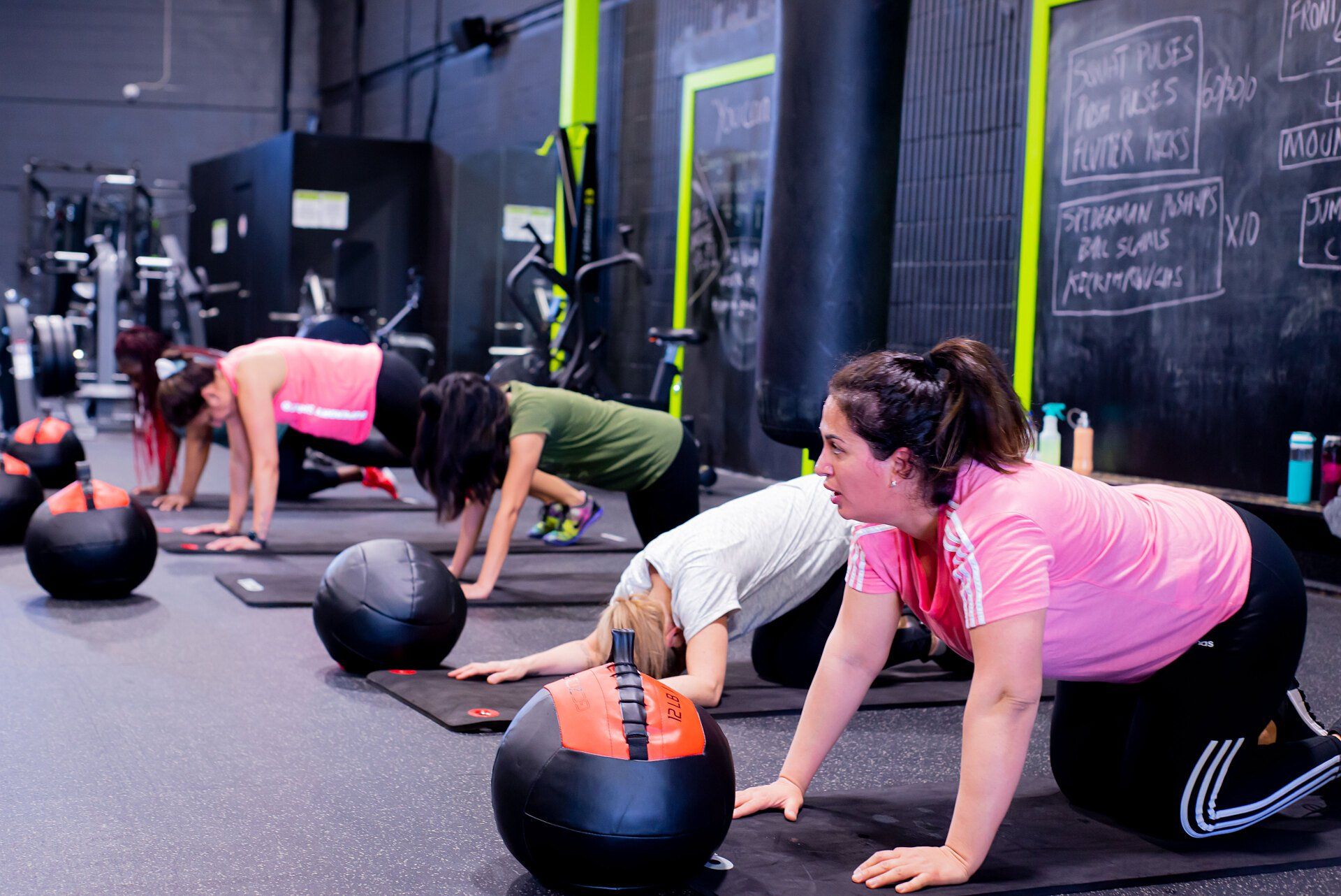 a group of women are doing push ups in a gym .