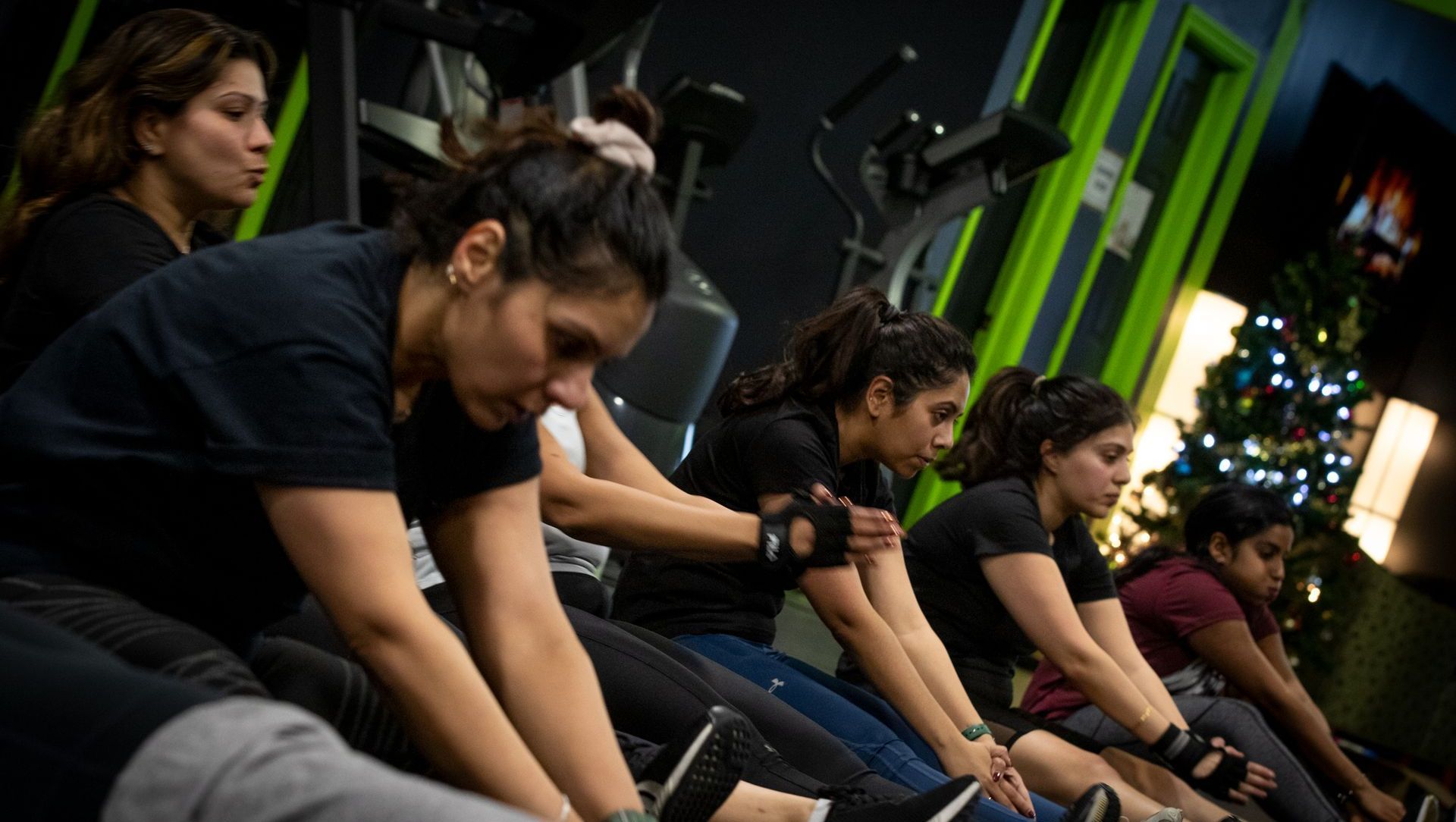 a group of women are stretching their legs in a gym .