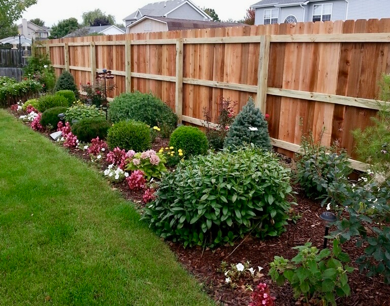 A wooden fence is along the side of a road.
