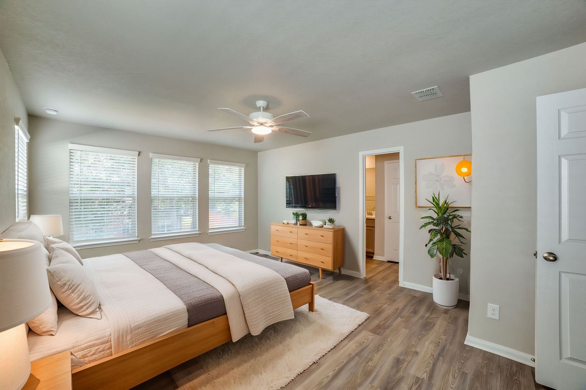 Bedroom with bed, dresser, TV, and door to bathroom. Windows on the left.