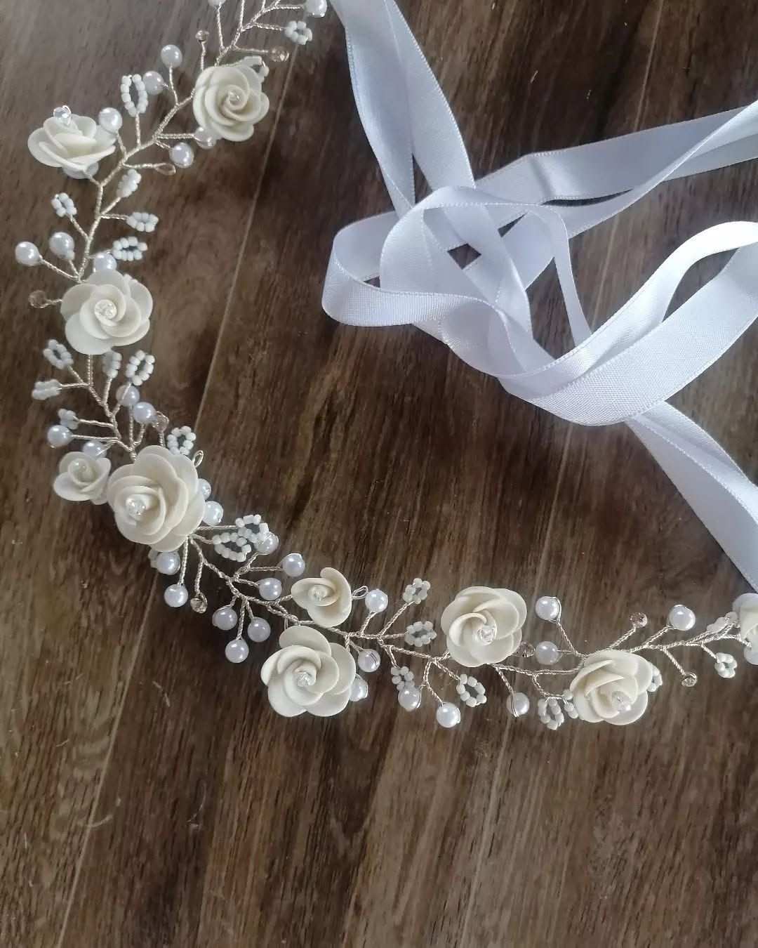 Delicada guirnalda floral blanca para el pelo, con cinta, sobre una superficie de madera