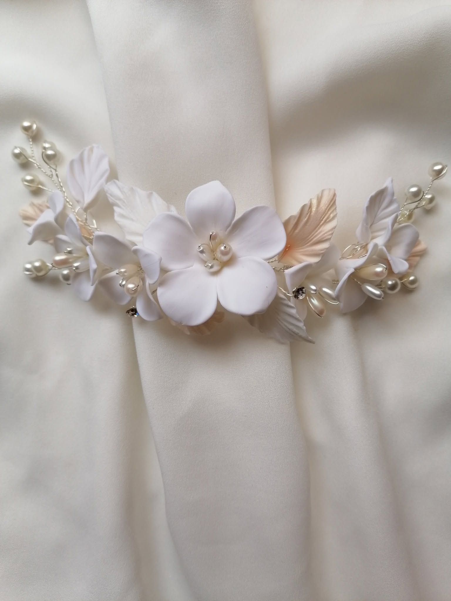 Cinturón nupcial floral blanco y de perlas, con delicadas hojas sobre tela de satén color marfil