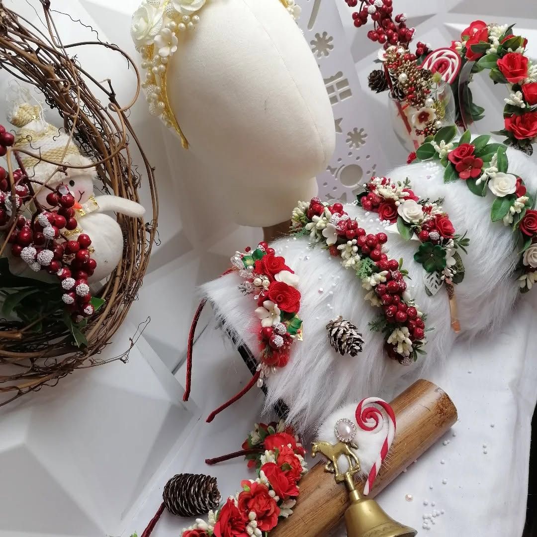 Exhibición navideña de manualidades con figuras de renos blancos, bayas rojas, piñas y una rama de canela sobre tela blanca