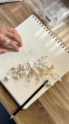 Piezas de cerámica con forma de flores, en blanco, azul y verde, dispuestas sobre una mesa junto a herramientas de modelado