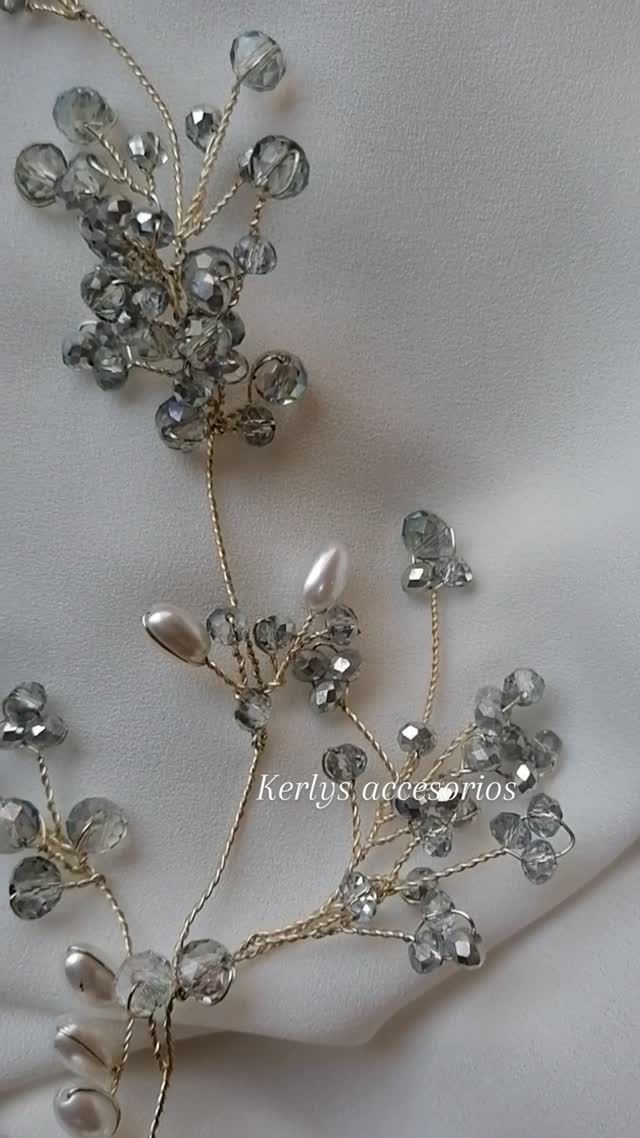 Accesorio floral plateado para el cabello con cuentas sobre un fondo de tela blanca