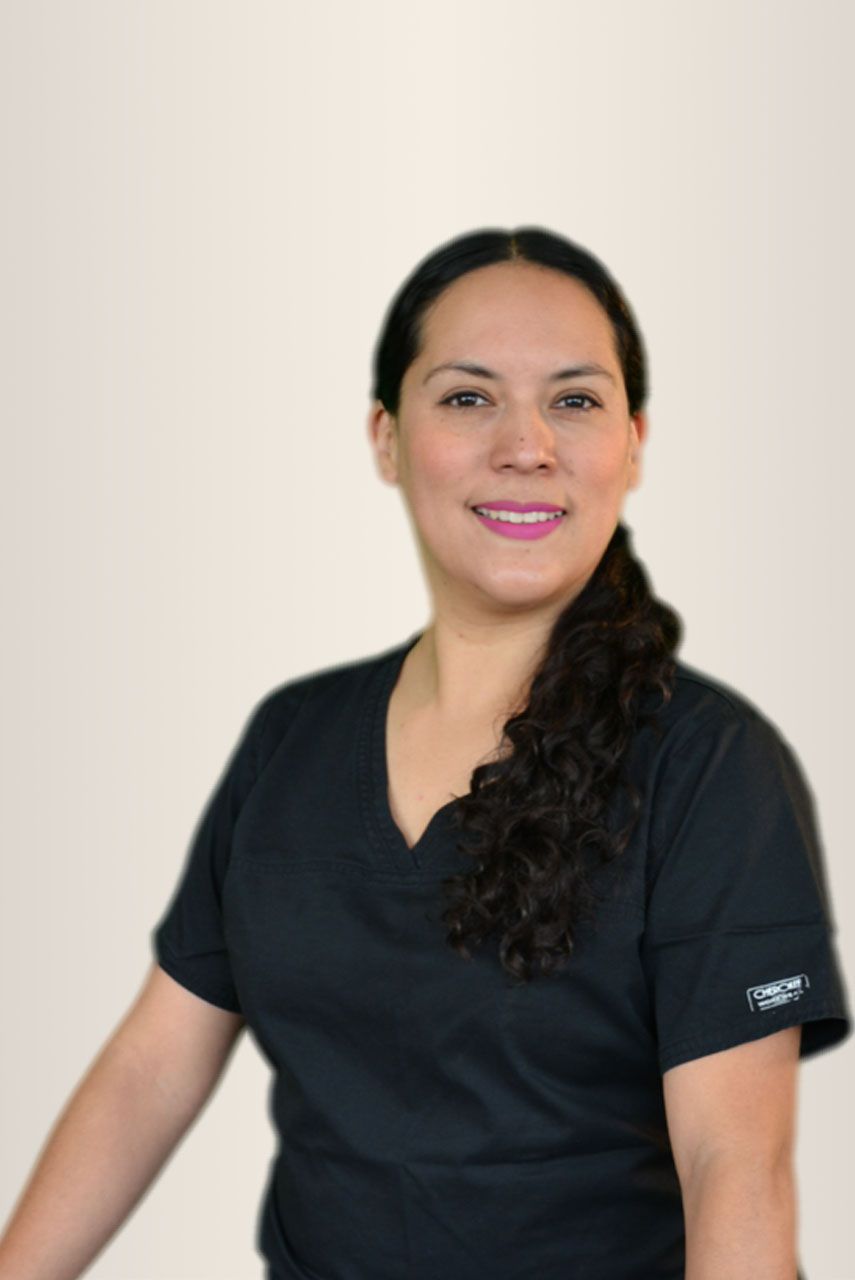 Mujer con uniforme negro, sonriente, con cabello oscuro, mirando a la cámara.