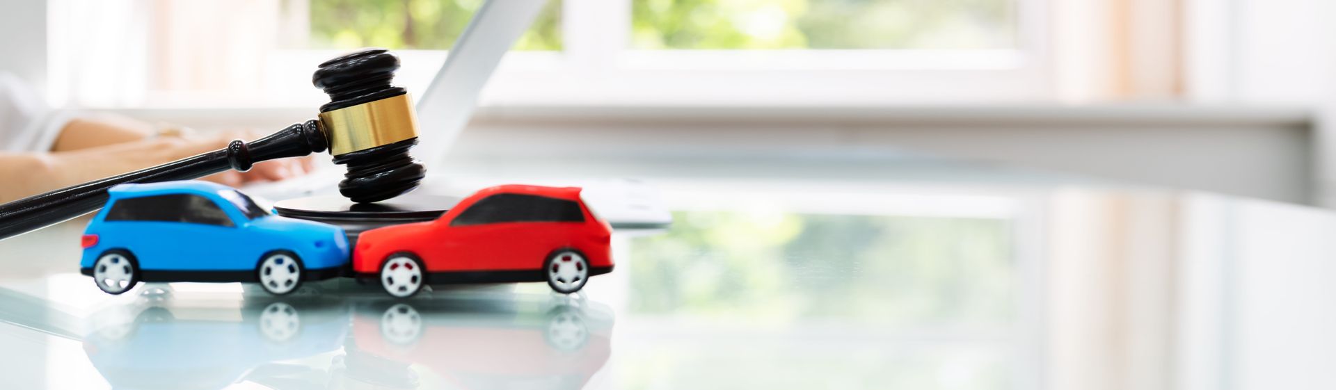 Toy cars with a judge’s gavel on top, symbolizing a car accident claim or legal dispute