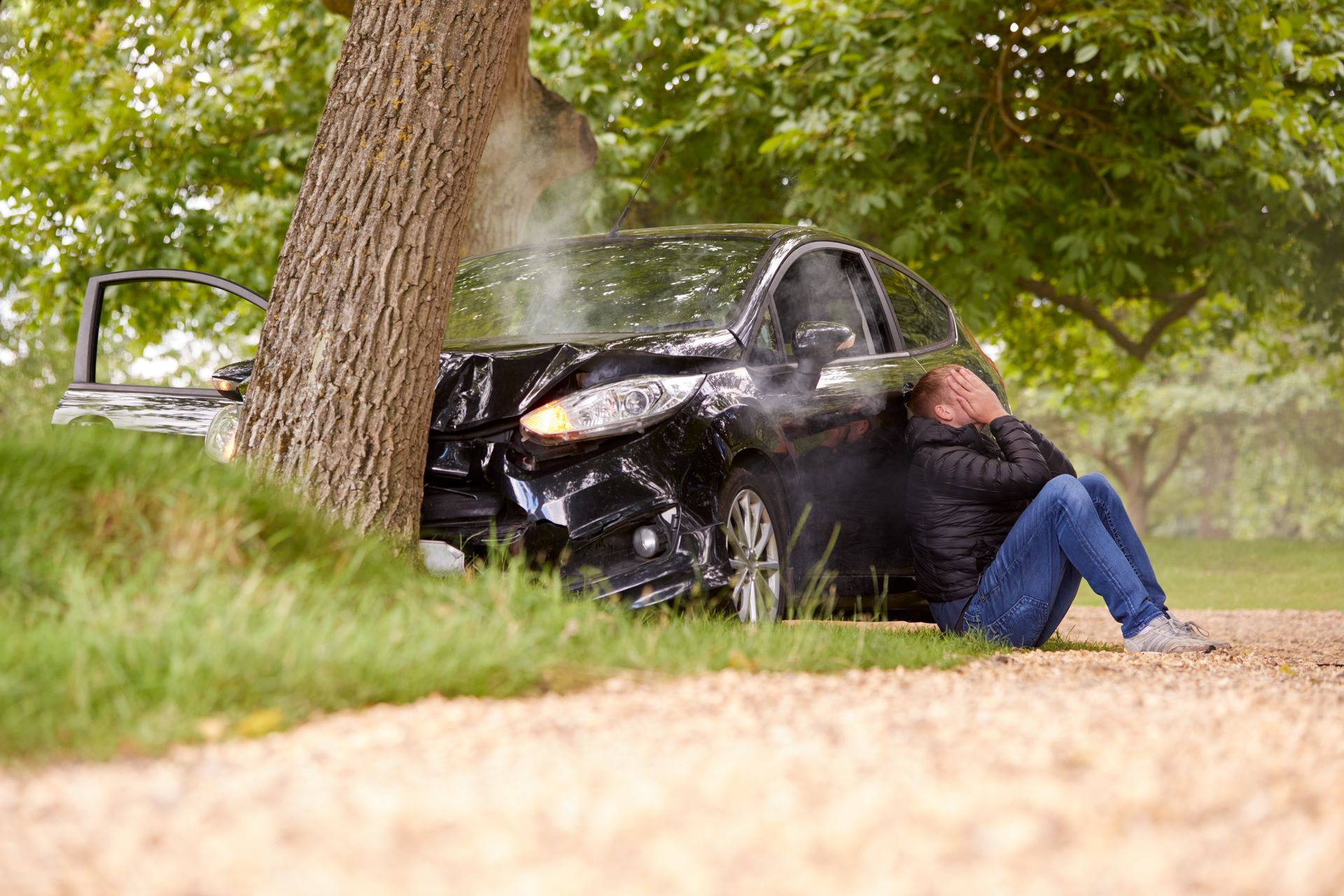 Person crouches near the vehicle, representing car accident claim in Georgia.