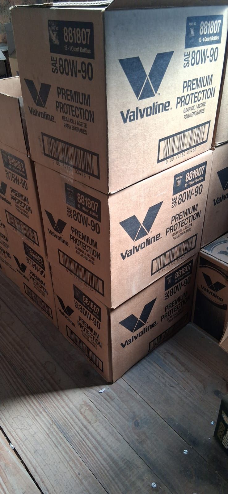 Cajas de cartón apiladas en una habitación de madera, impresas con logotipos azules y negros.