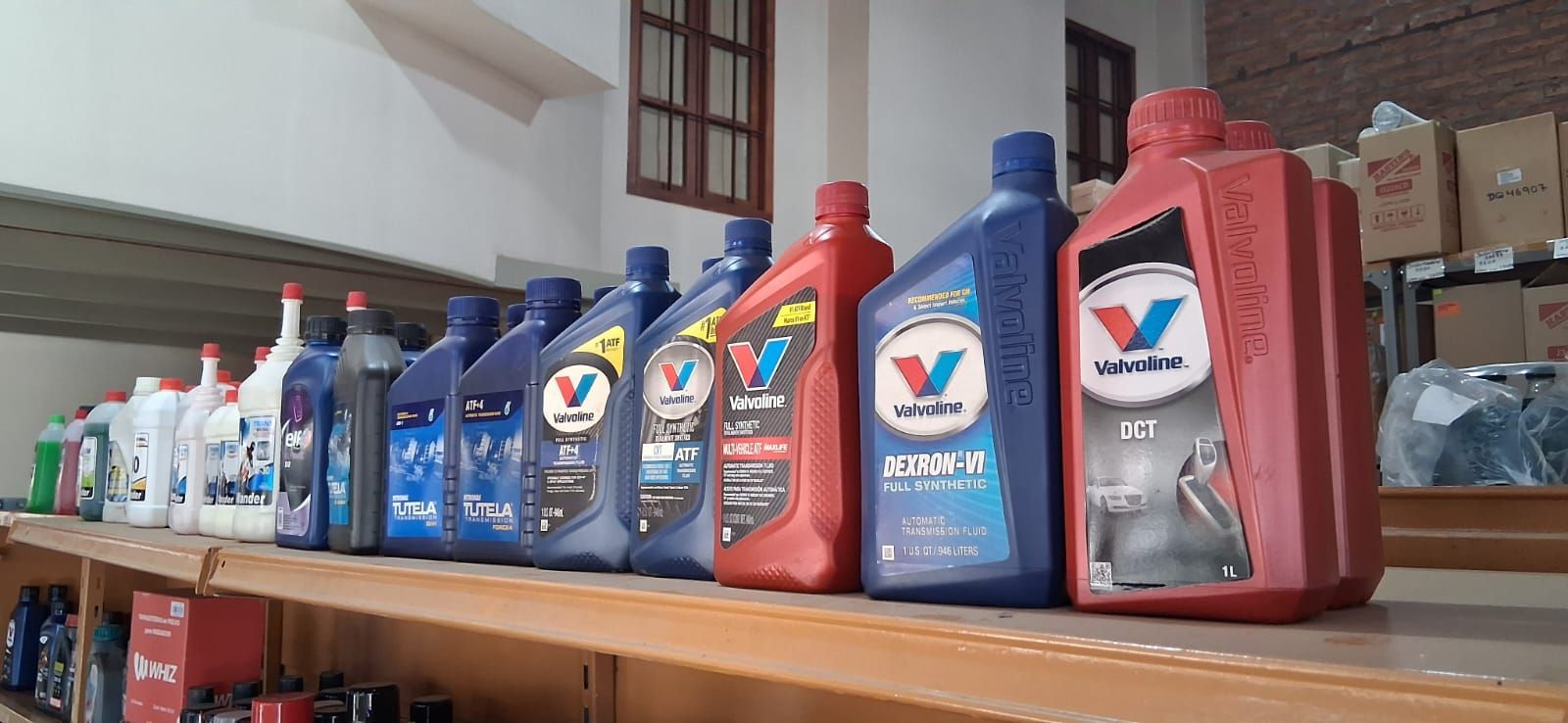 Filas de botellas de aceite de motor en azul, rojo y blanco en un estante de la tienda.