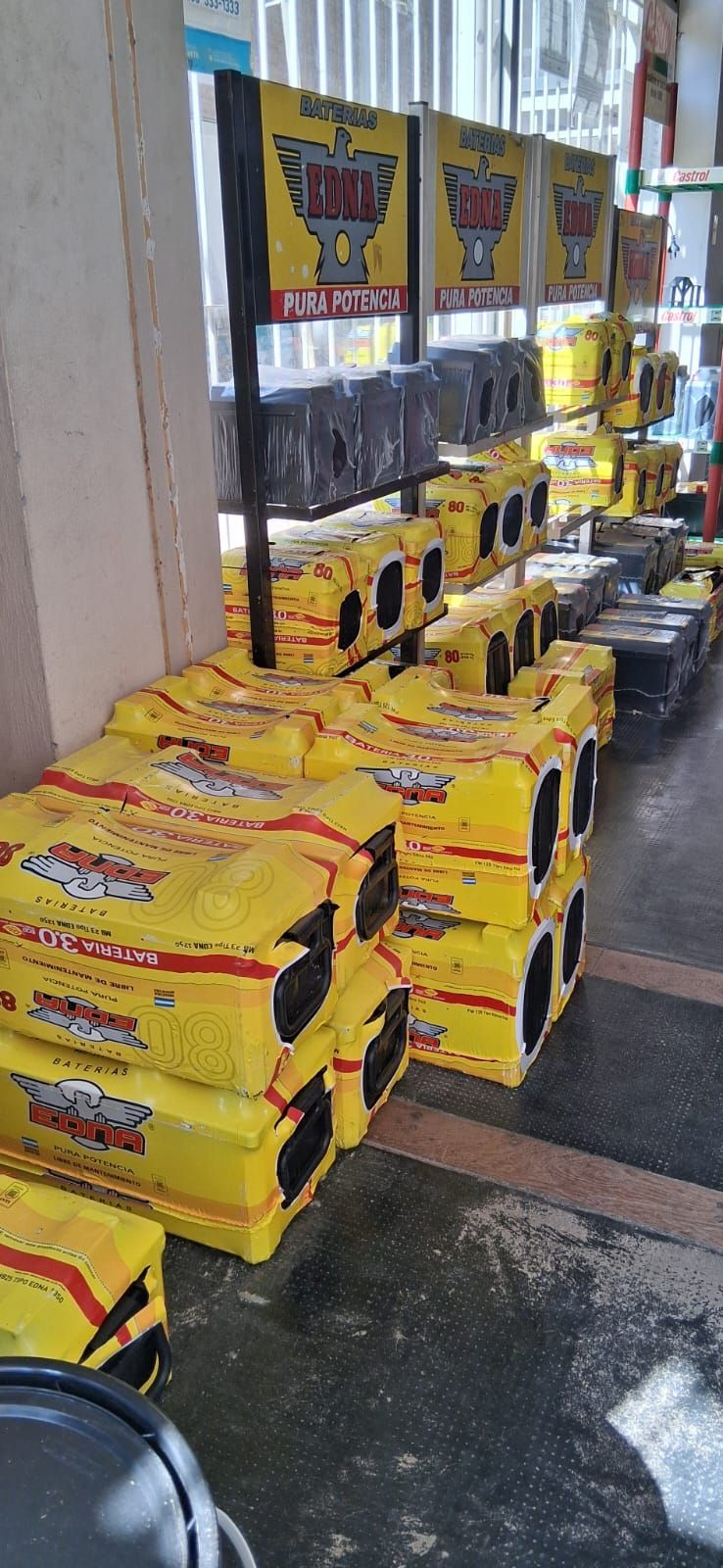 Productos empaquetados de color amarillo apilados en un expositor en la acera, junto a la ventana de una tienda.