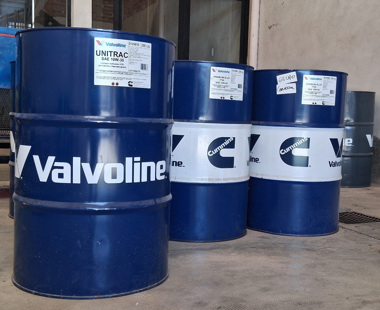 Bidones de aceite azul Valvoline apilados en un almacén, con otros barriles azules detrás.