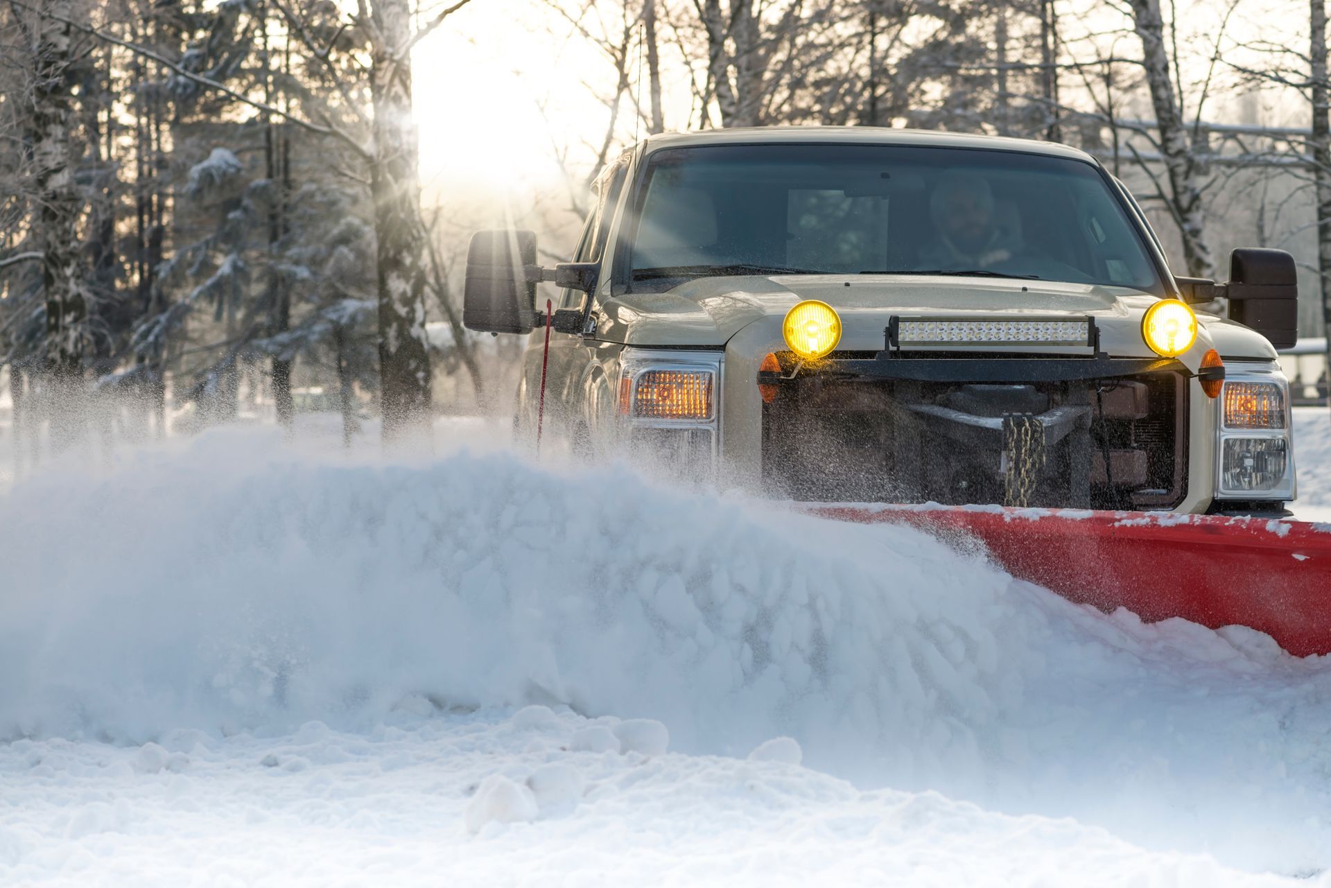 Un camion déneige une route enneigée.