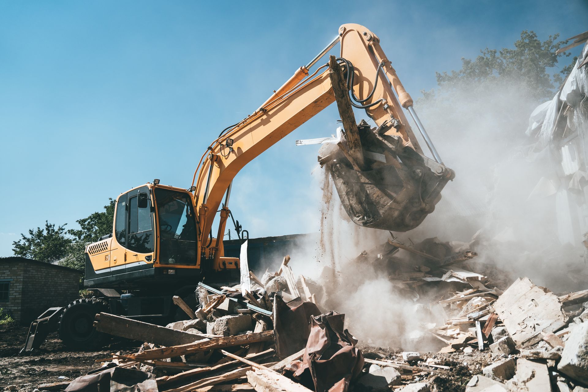 Une excavatrice jaune démolit un bâtiment.