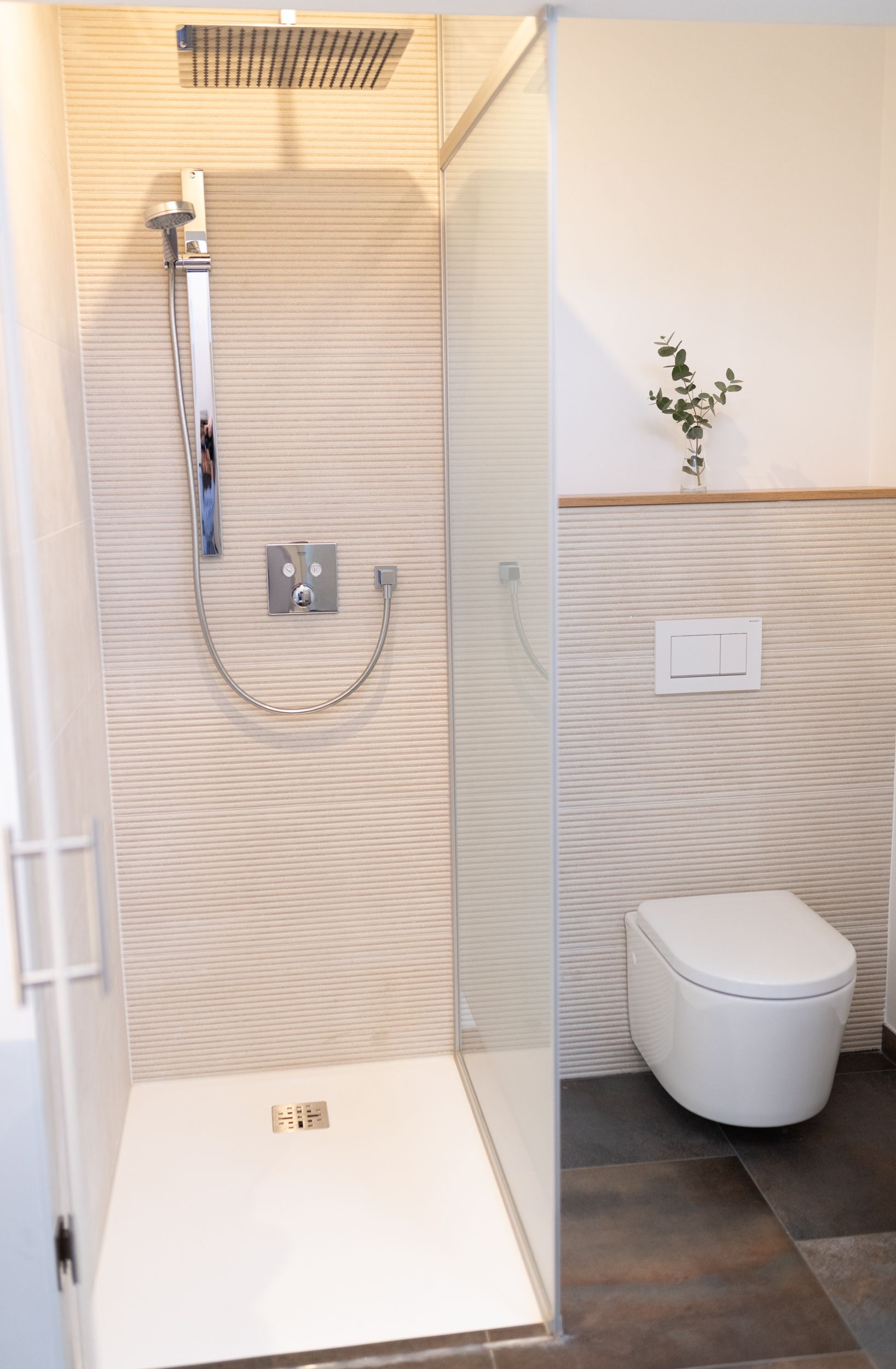 Hotel Maria, Badezimmer mit begehbarer Dusche, abgetrennt mit einer Glaswand. Die Fliesen sind beige strukturiert. 