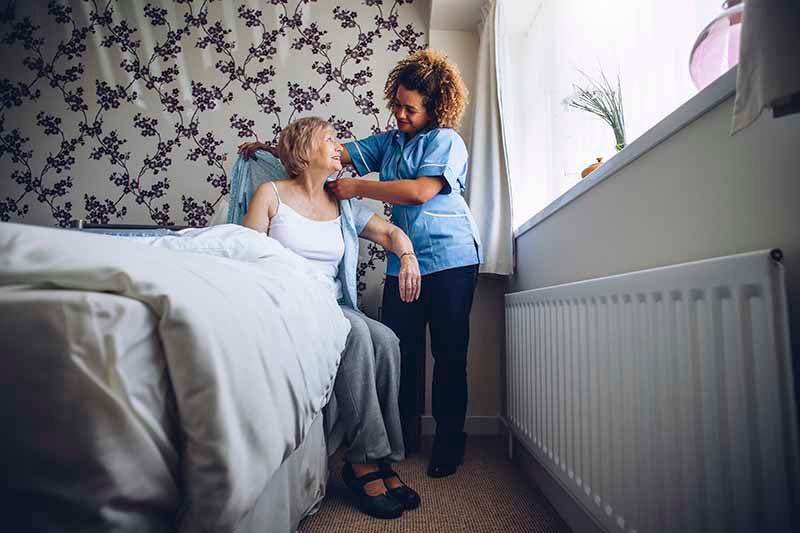 Eine Pflegerin hilft einer Seniorin in ihrem eigenen Zuhause. Stockfoto