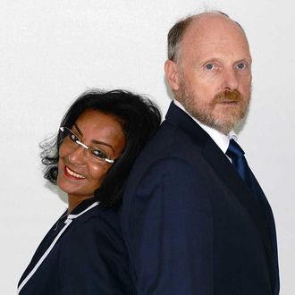 Zwei Geschäftsleute in Businesskleidung stehen Rücken an Rücken vor einem schlichten weißen Hintergrund.