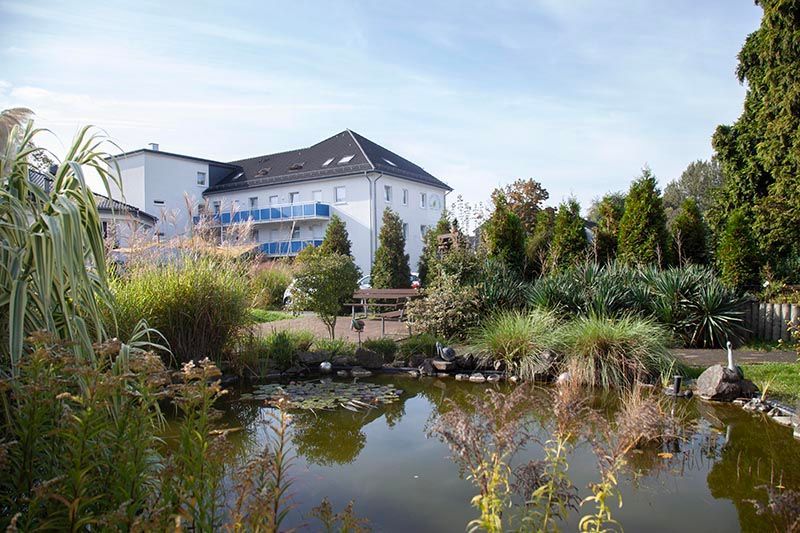 Wohnpark in Oberhausen-Osterfeld. Weißes Gebäude mit Teichanlage