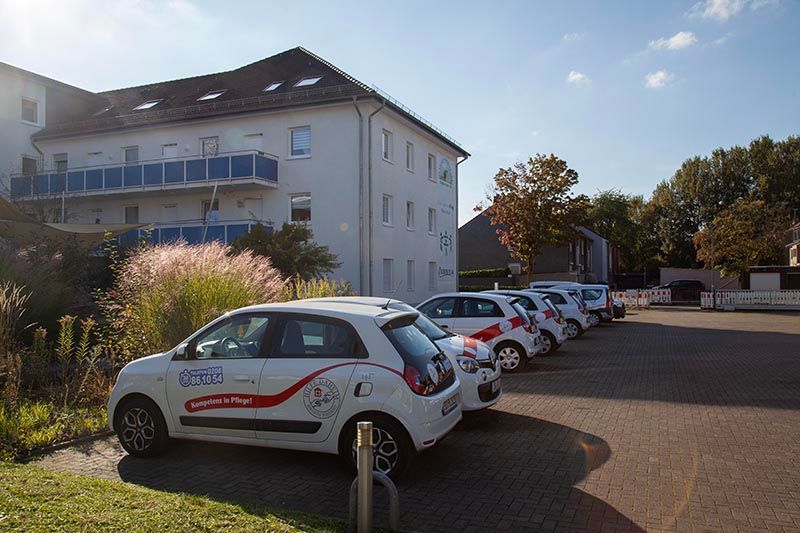 Betriebsstätte ambulante Pflege. Vor dem Haus stehen mehrere Dienstfahrzeuge, Rückansicht