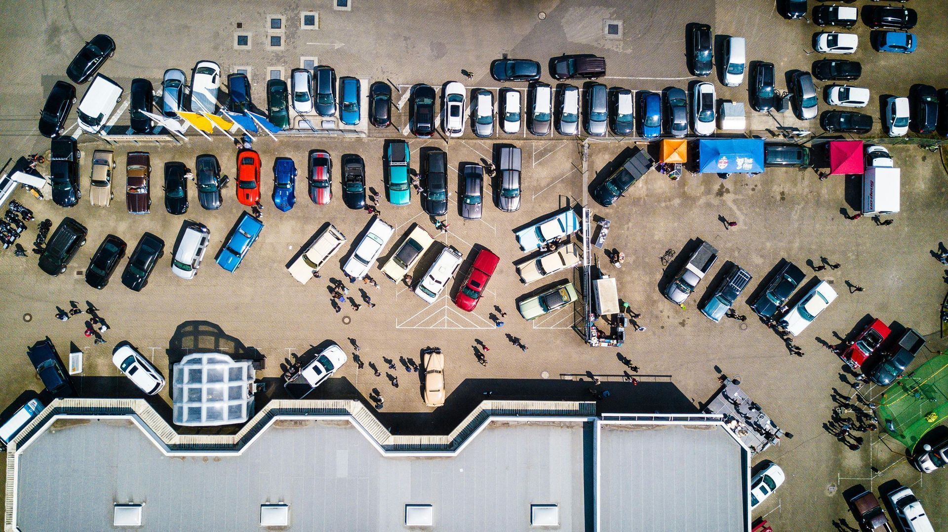 An aerial view of a lot of cars parked in front of a building