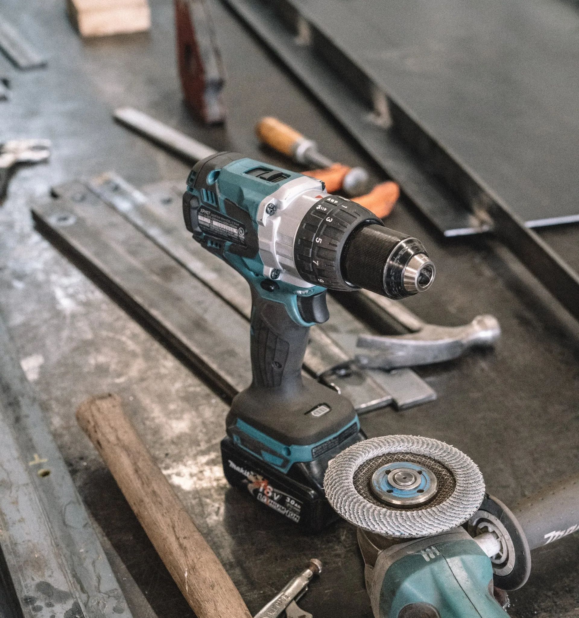 A drill , grinder , hammer and other tools are on a table.