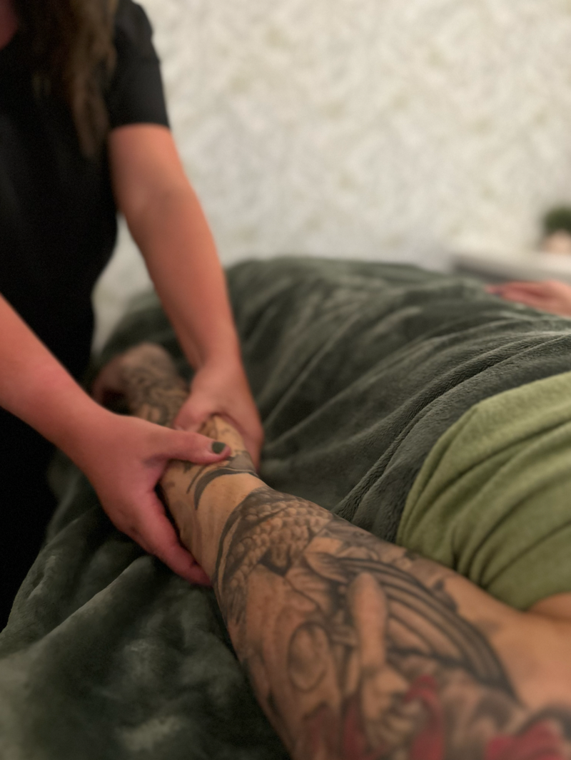 A woman with a tattoo on her arm is getting a massage.