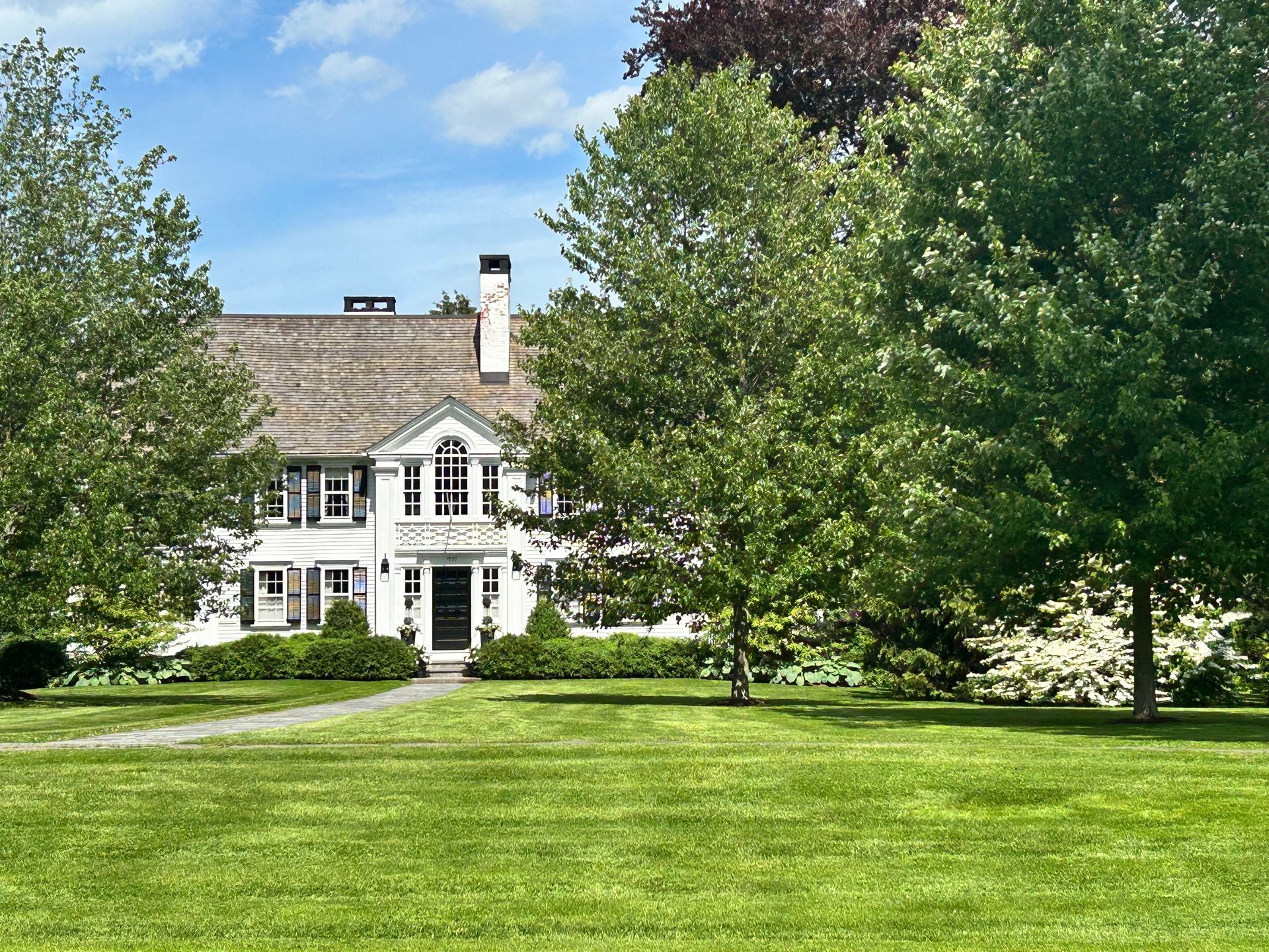 A large white house with a lush green lawn in front of it.