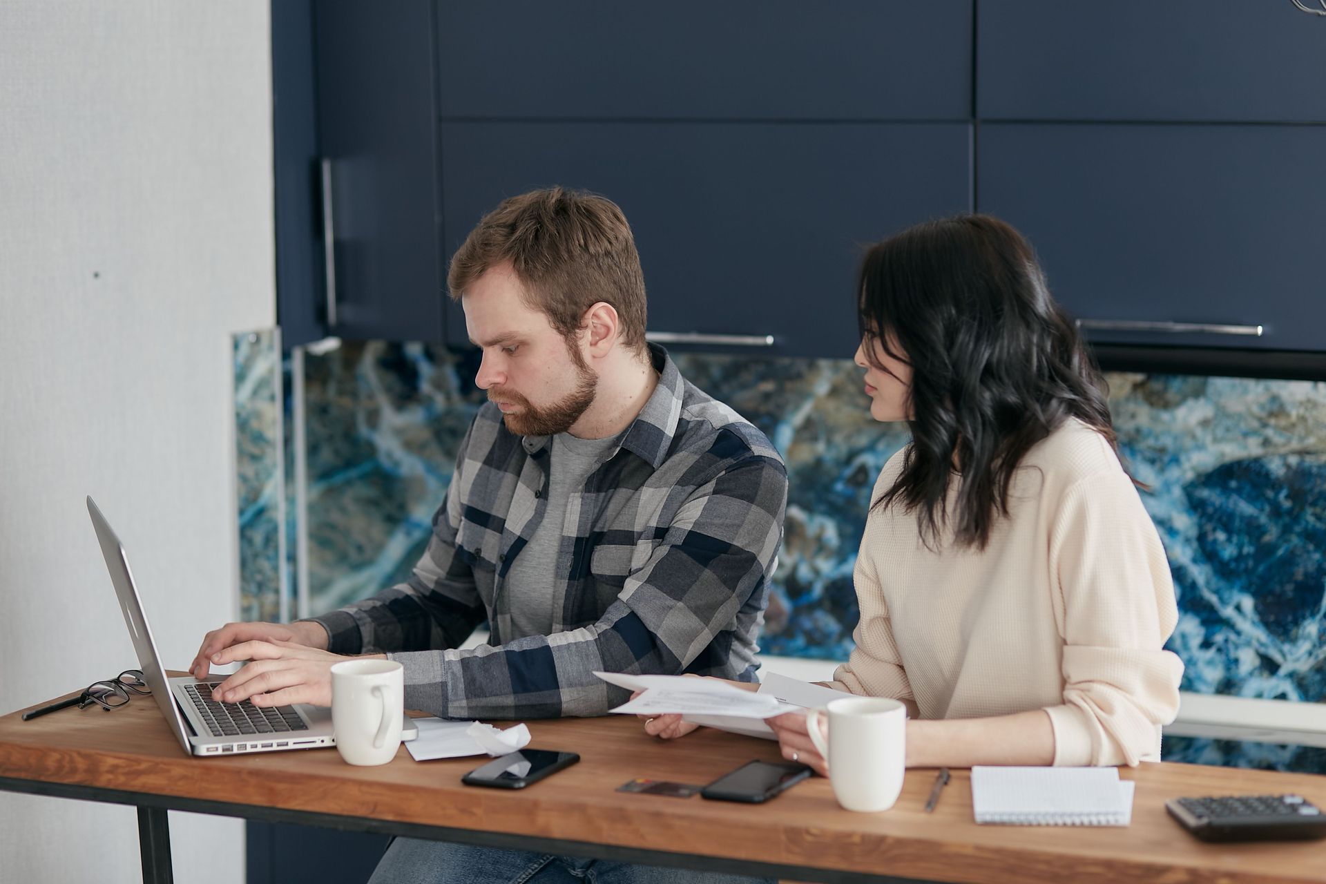 Two coworkers seated at a table, working on laptops in a modern office room