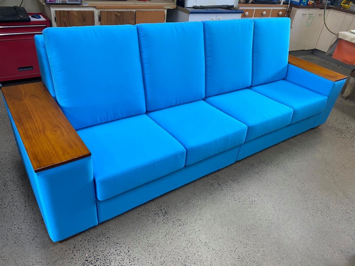 A Blue Couch With Wooden Arm Rests Is Sitting On A Concrete Floor — Aztak Upholstery In Mareeba, QLD
