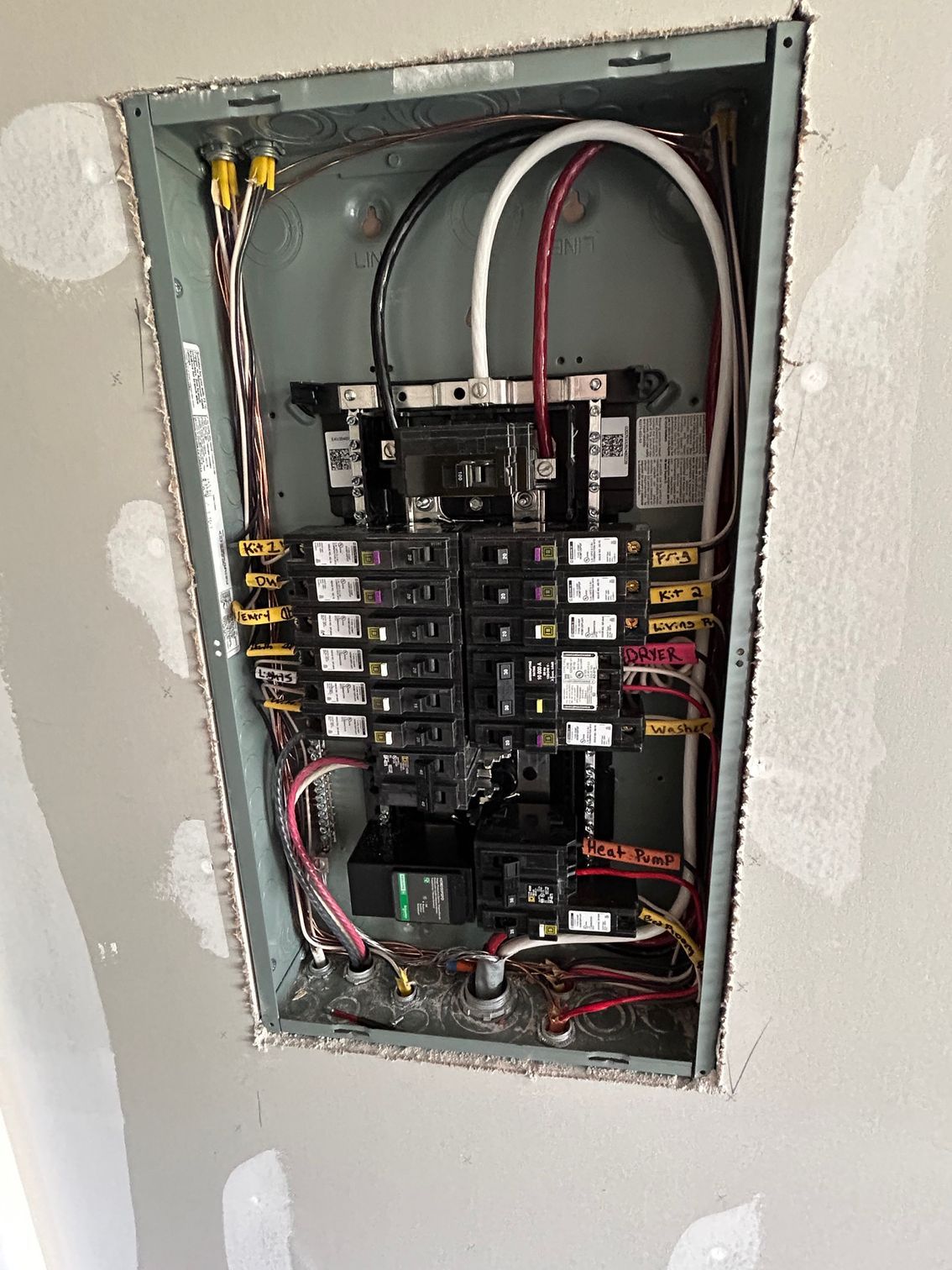 Open electrical breaker panel with exposed wiring in a wall recess