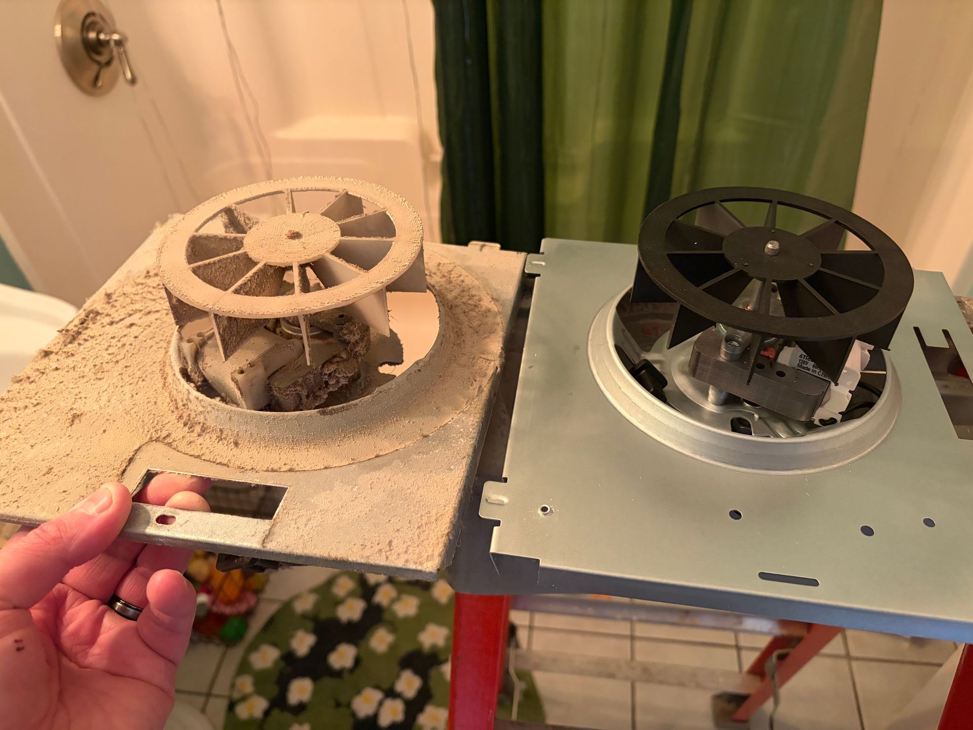 Two tabletop fans side by side, one dusty white and one black, with a hand holding the left unit.