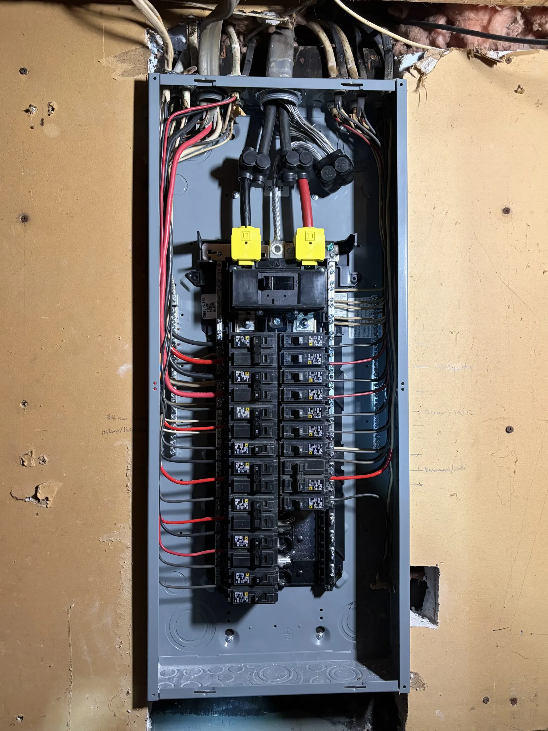 Open electrical breaker panel with exposed wiring and two yellow switches