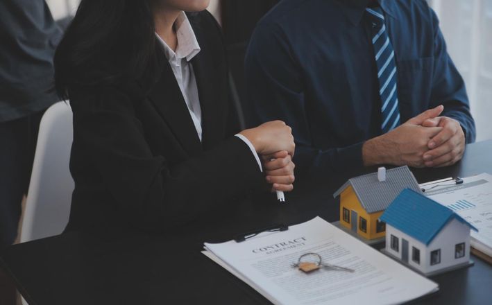 Business meeting with two people beside house model and document on a table