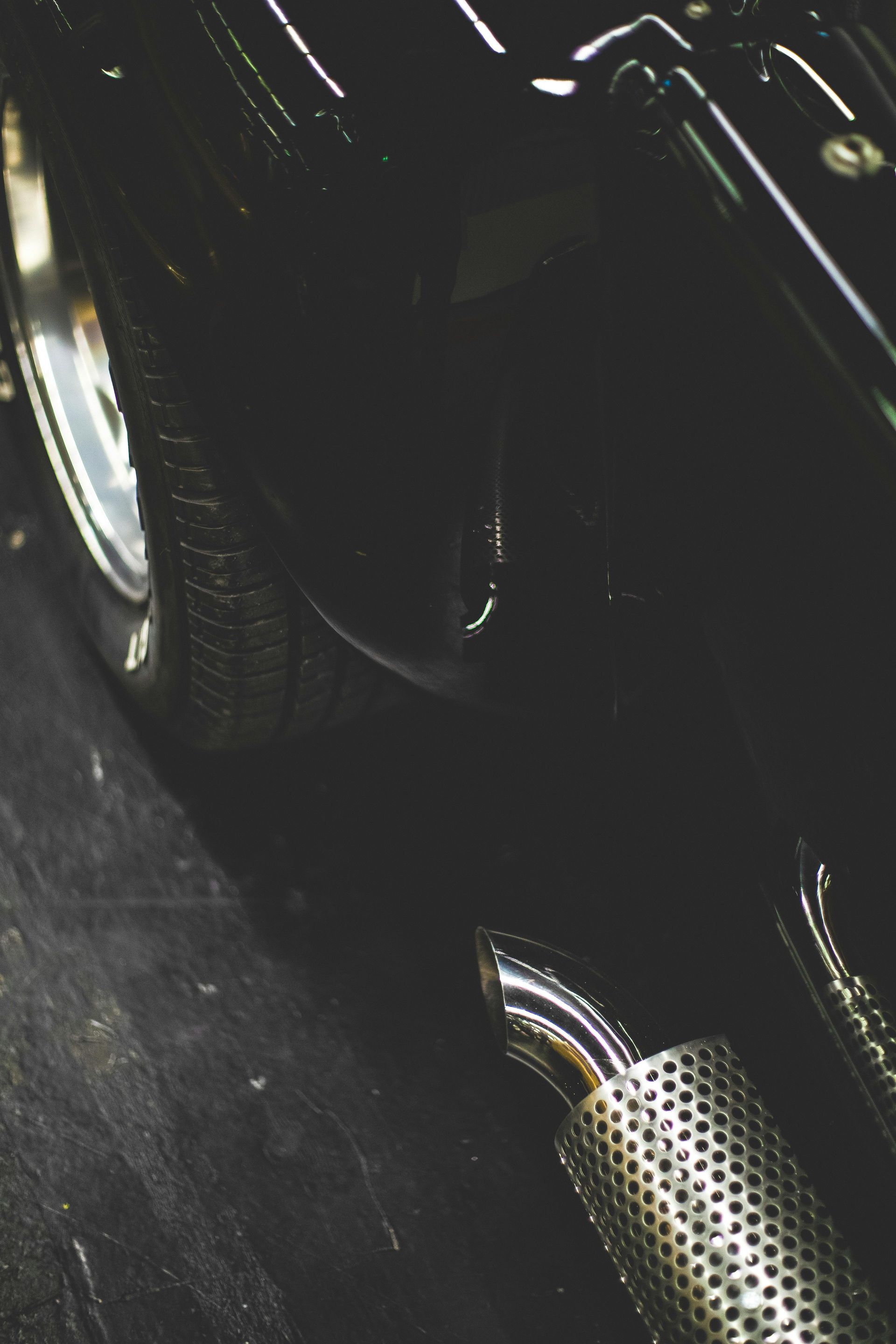 Chrome exhaust pipe on a black car; tire and body details visible.