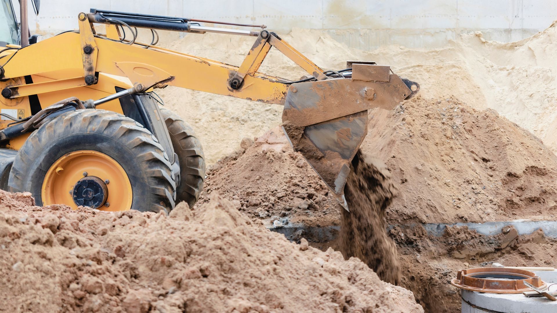 Yellow backhoe digging sand at a construction site