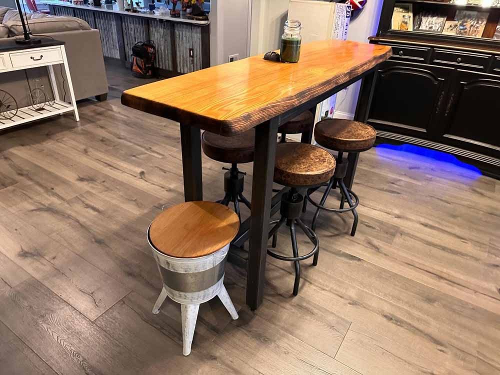 Bar table with three stools, one unique metal and wood stool, in a home setting.