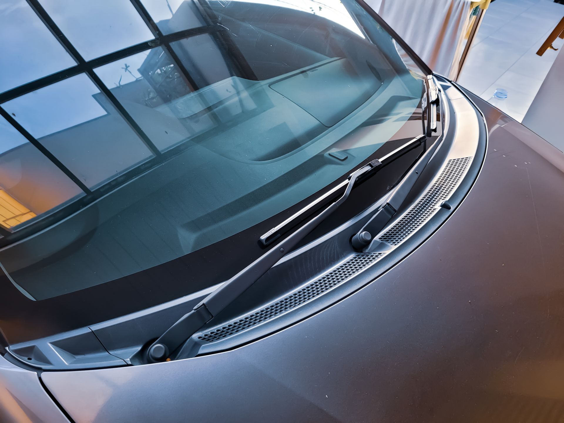 Close-up of a car windshield with wipers and reflections on the glass
