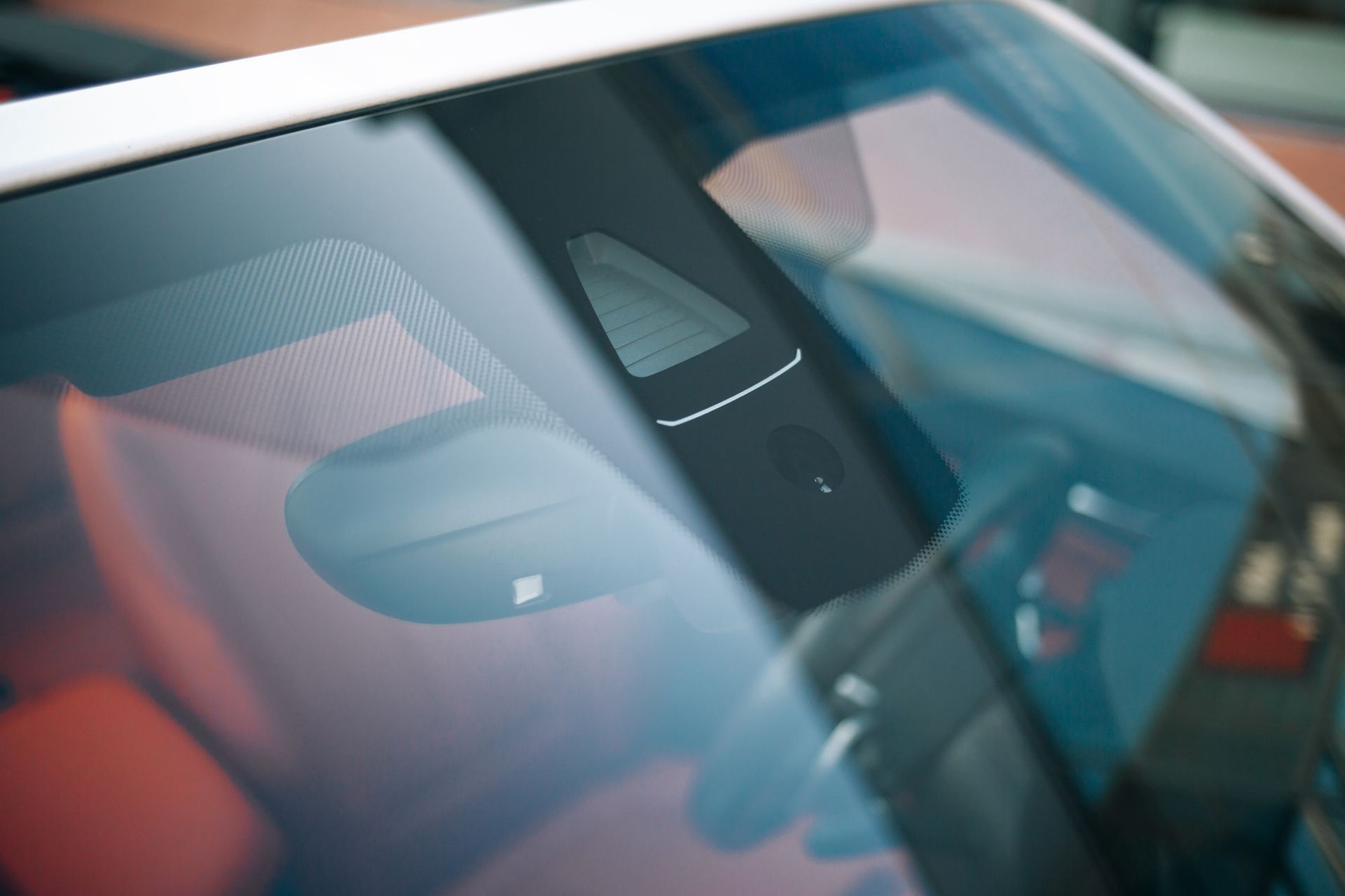 Close-up of a car windshield with reflections and a rearview mirror visible inside