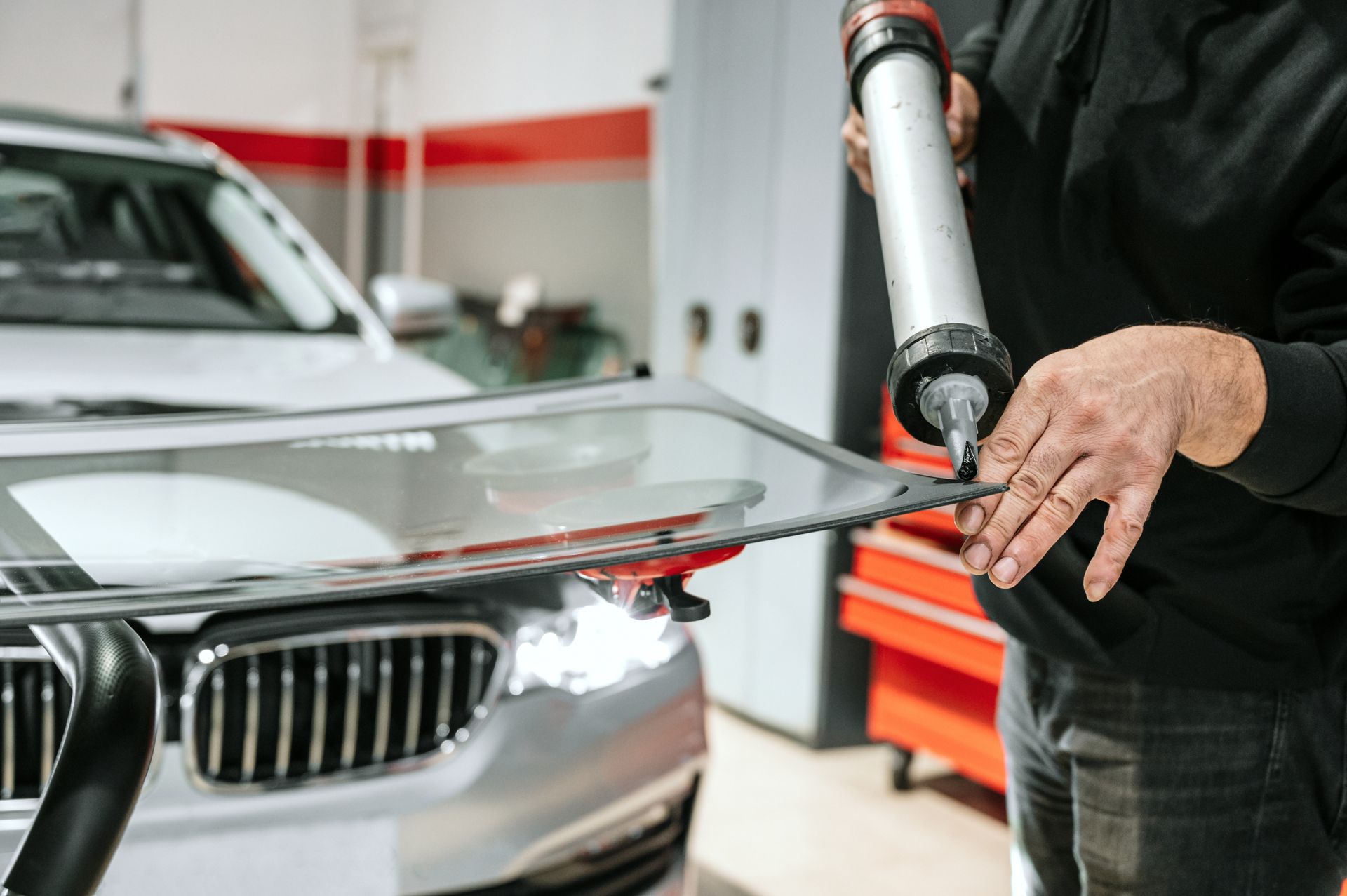 Car windshield being sealed with adhesive in an auto repair shop