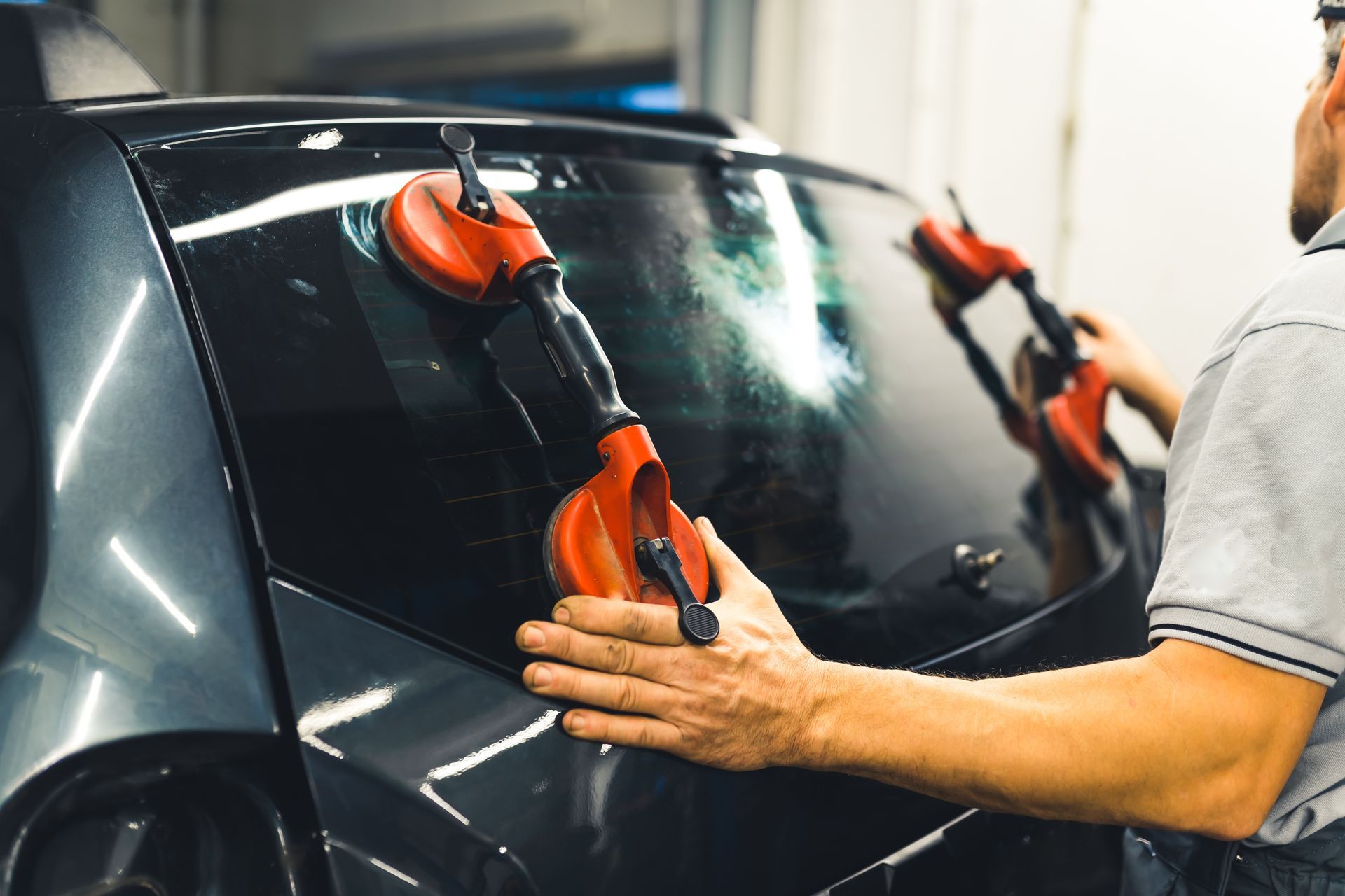 Person polishing a black car with red polishing tools in a garage