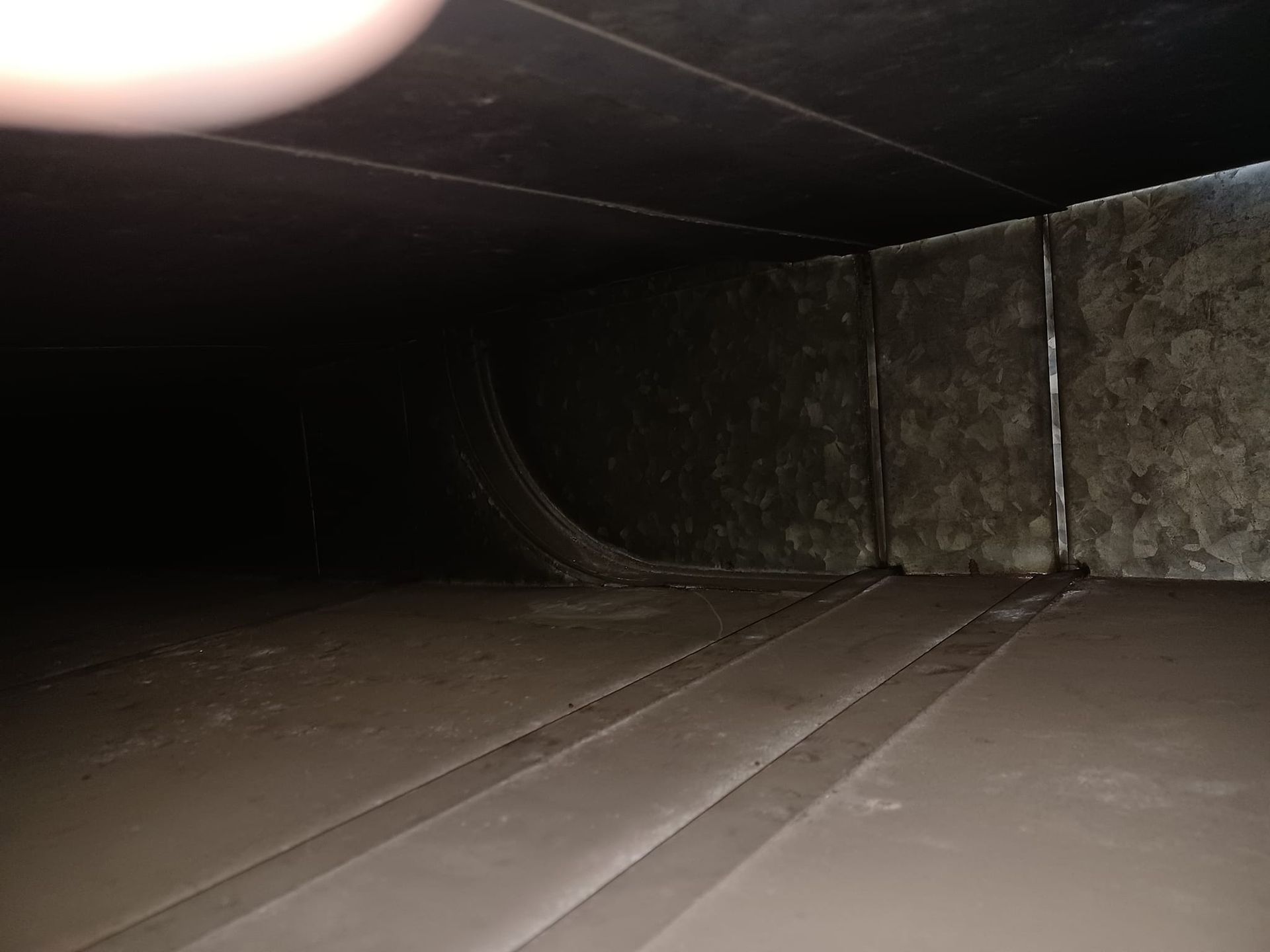A person is taking a picture of the inside of a duct.