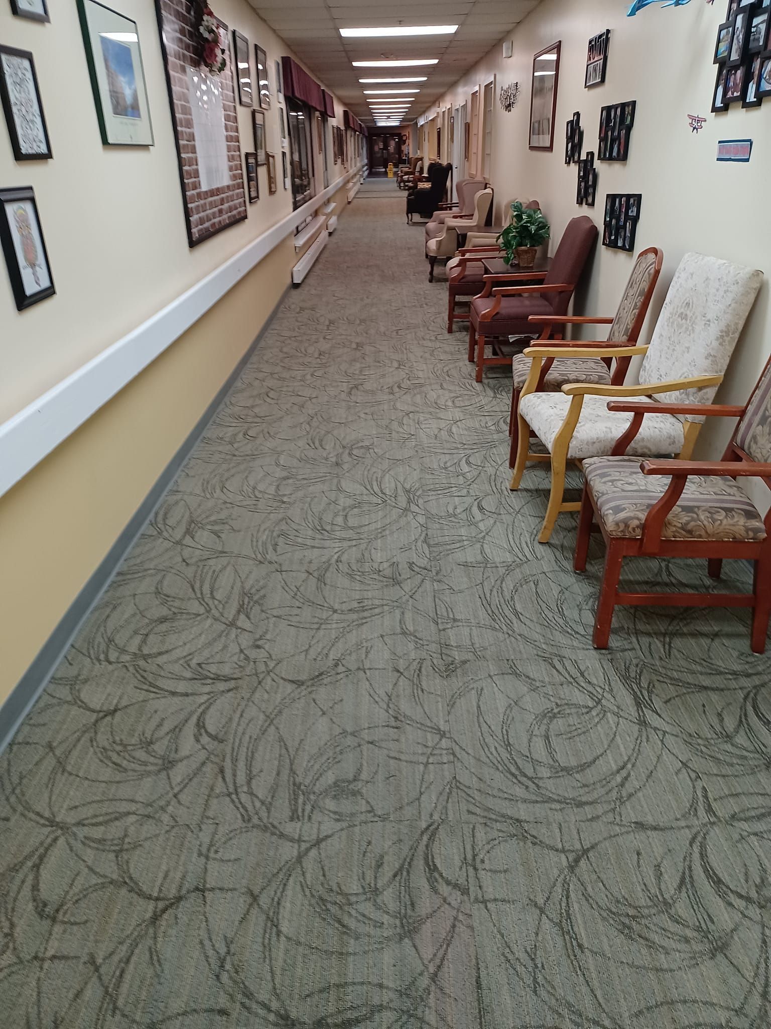 A long hallway with chairs and pictures on the wall.