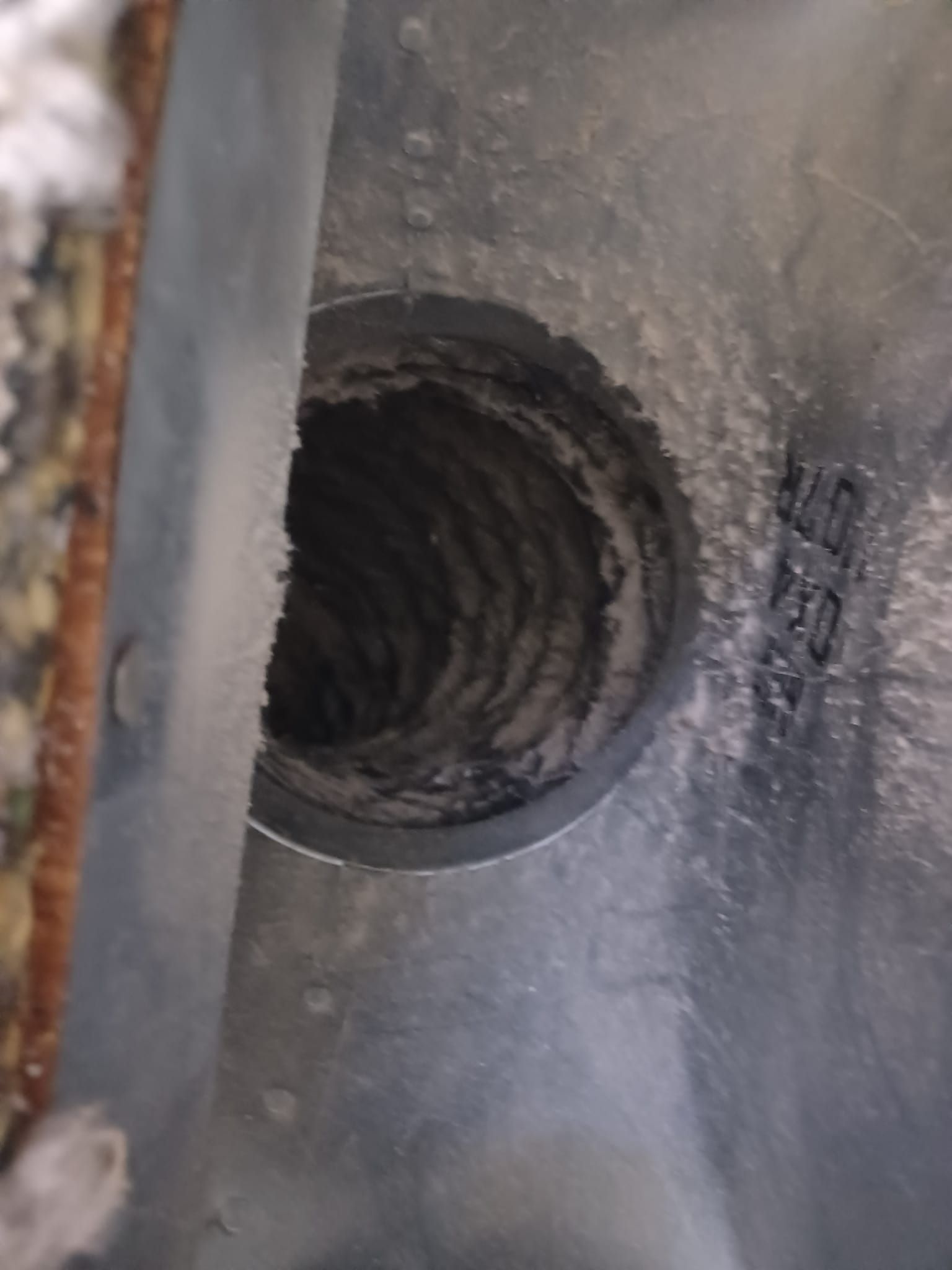 A close up of a dirty air duct with a hole in it.