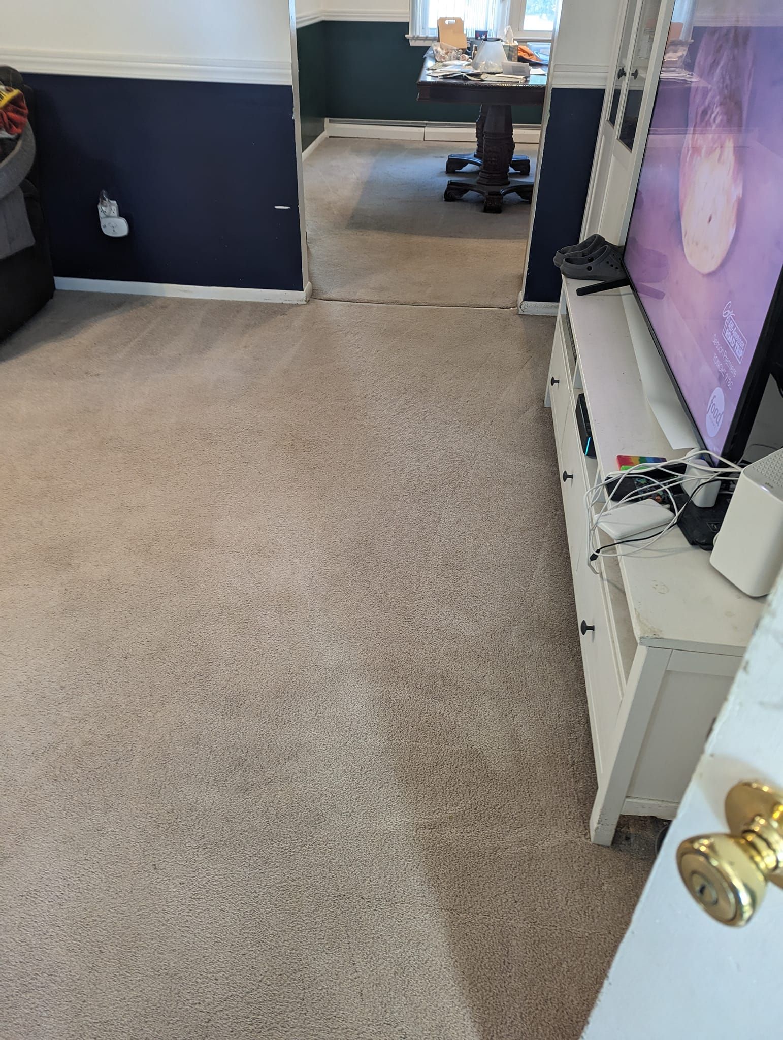 A living room with a carpeted floor and a flat screen tv on a stand.