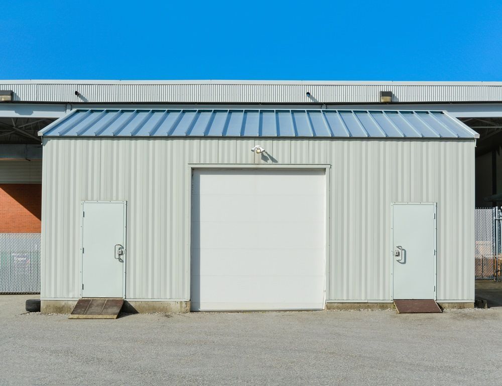 A Metal Warehouse Building with a Large Central Roll-up Door — Whit Coast Sheds in Gregory River, QLD