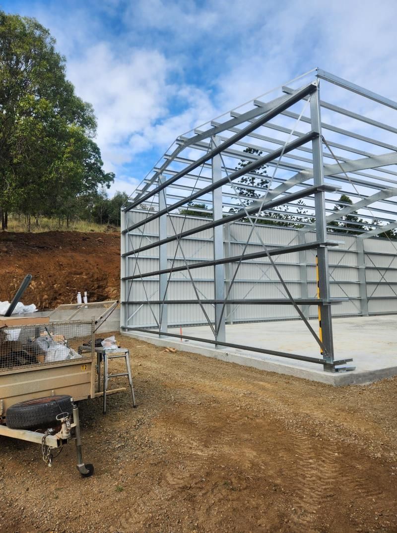 A Large Metal Structure Is Being Built In The Middle Of A Dirt Field — Whit Coast Sheds in  Gregory River, QLD