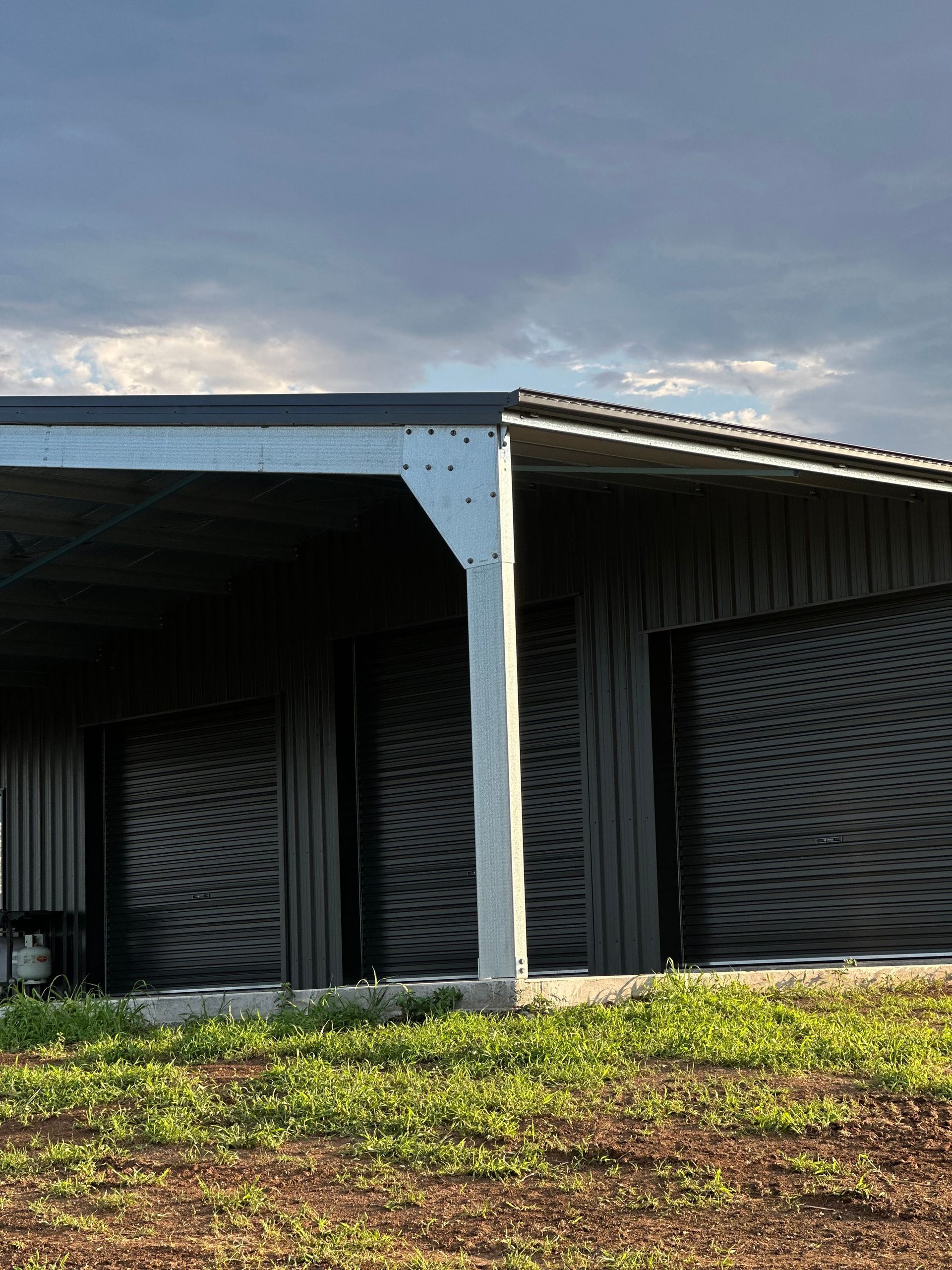 A Modern Dark Gray Metal Shed with a Concrete Support Beam Stands — Whit Coast Sheds in Gregory River, QLD